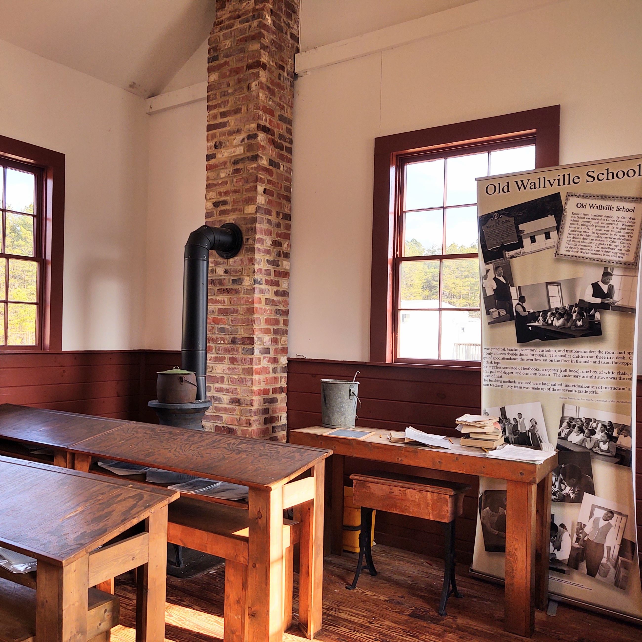 Inside of the Old Wallville School with desks, a furnace and an informational sign