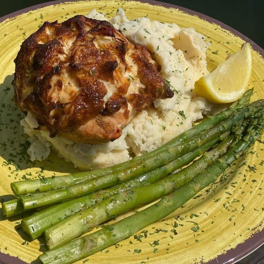 Crab cake and asparagus over mashed potatoes and a lemon