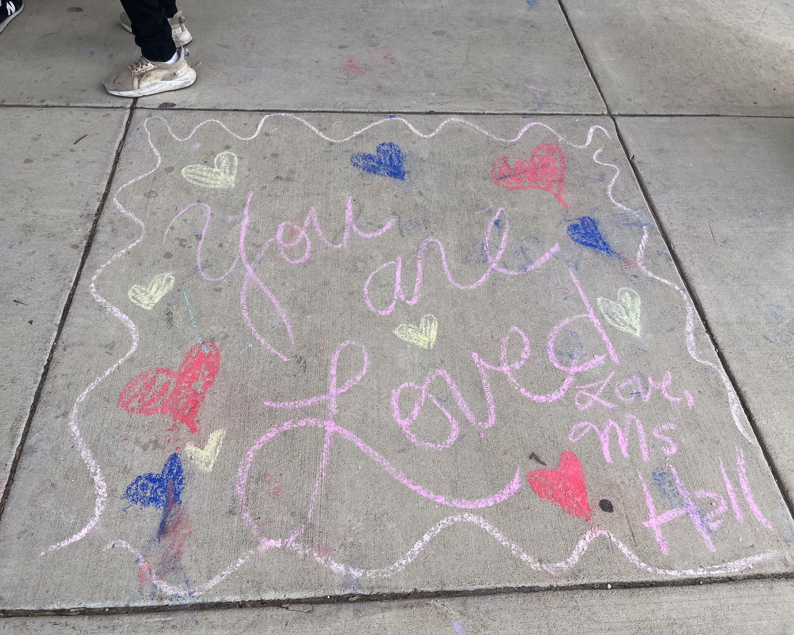Chalk art of hands making a heart around a heart with text "You matter."