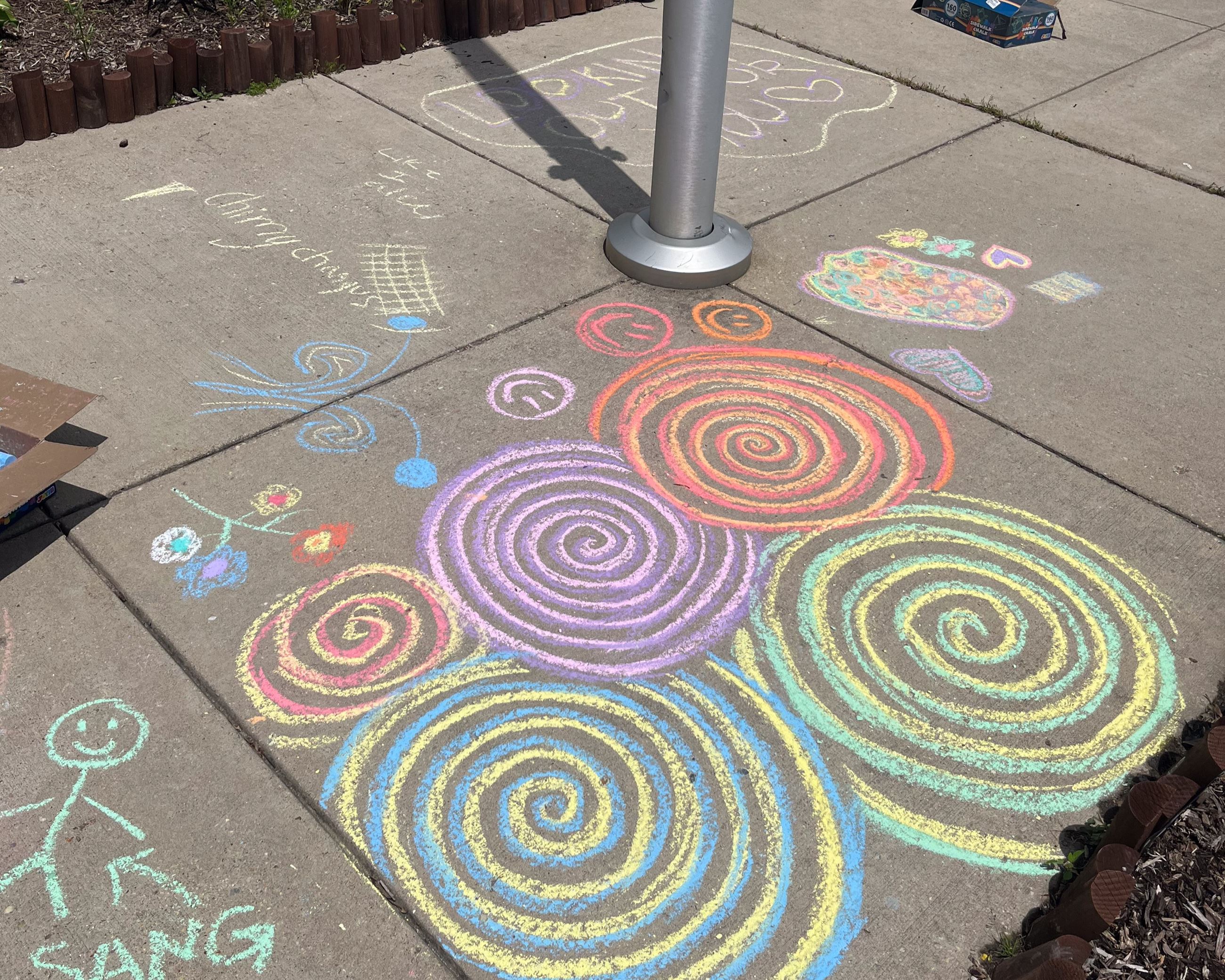 Multicolored chalk art hearts surrounding purple text "You are loved. Love, Ms. Hall."