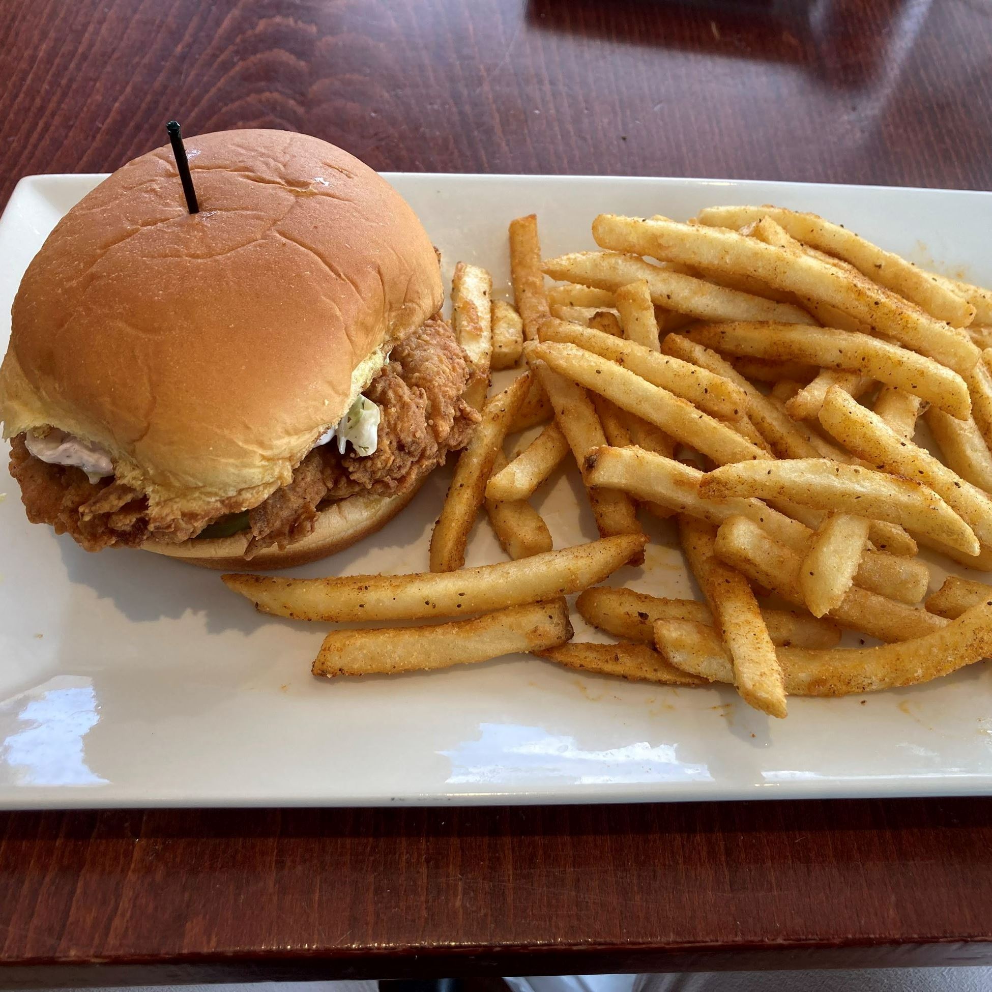 Chicken sandwich and fries on a white platter